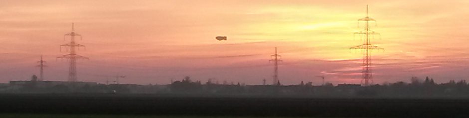Sonnenuntergang mit Hochspannungsmasten und Zeppelin